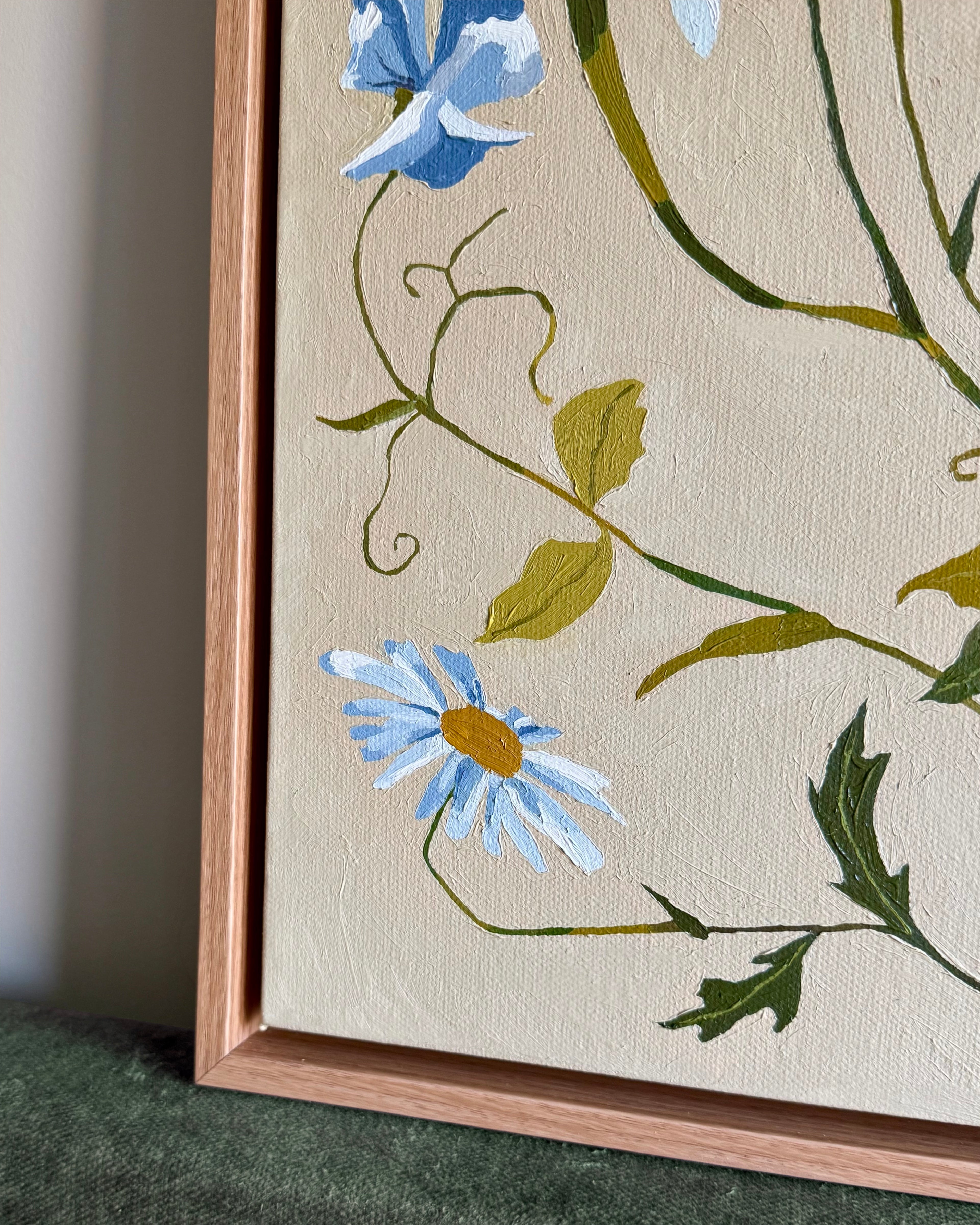 The corner of a framed painting showing a daisy and a sweet-pea.