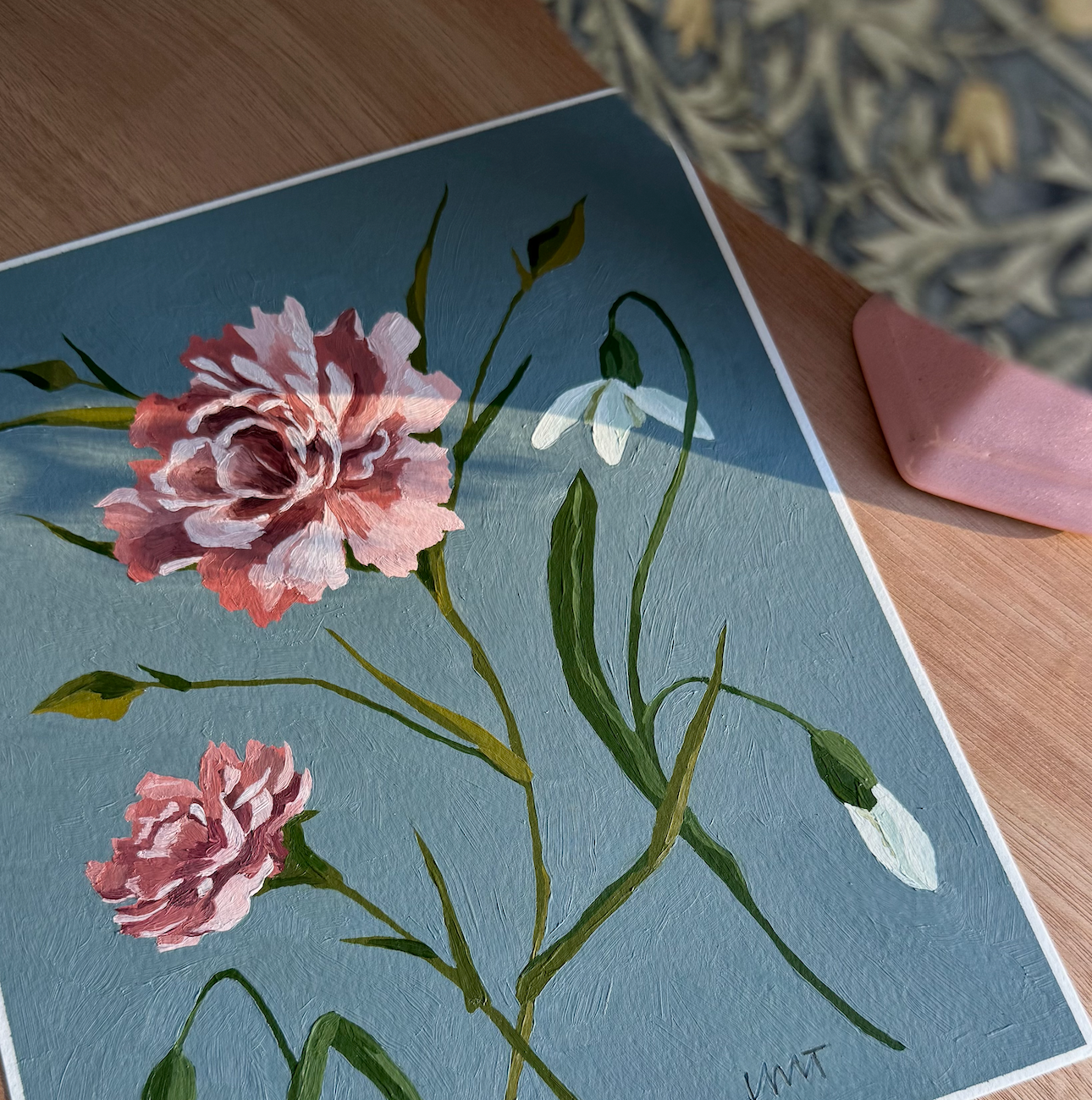 Floral painting on a blue background with pink flowers and green leaves.