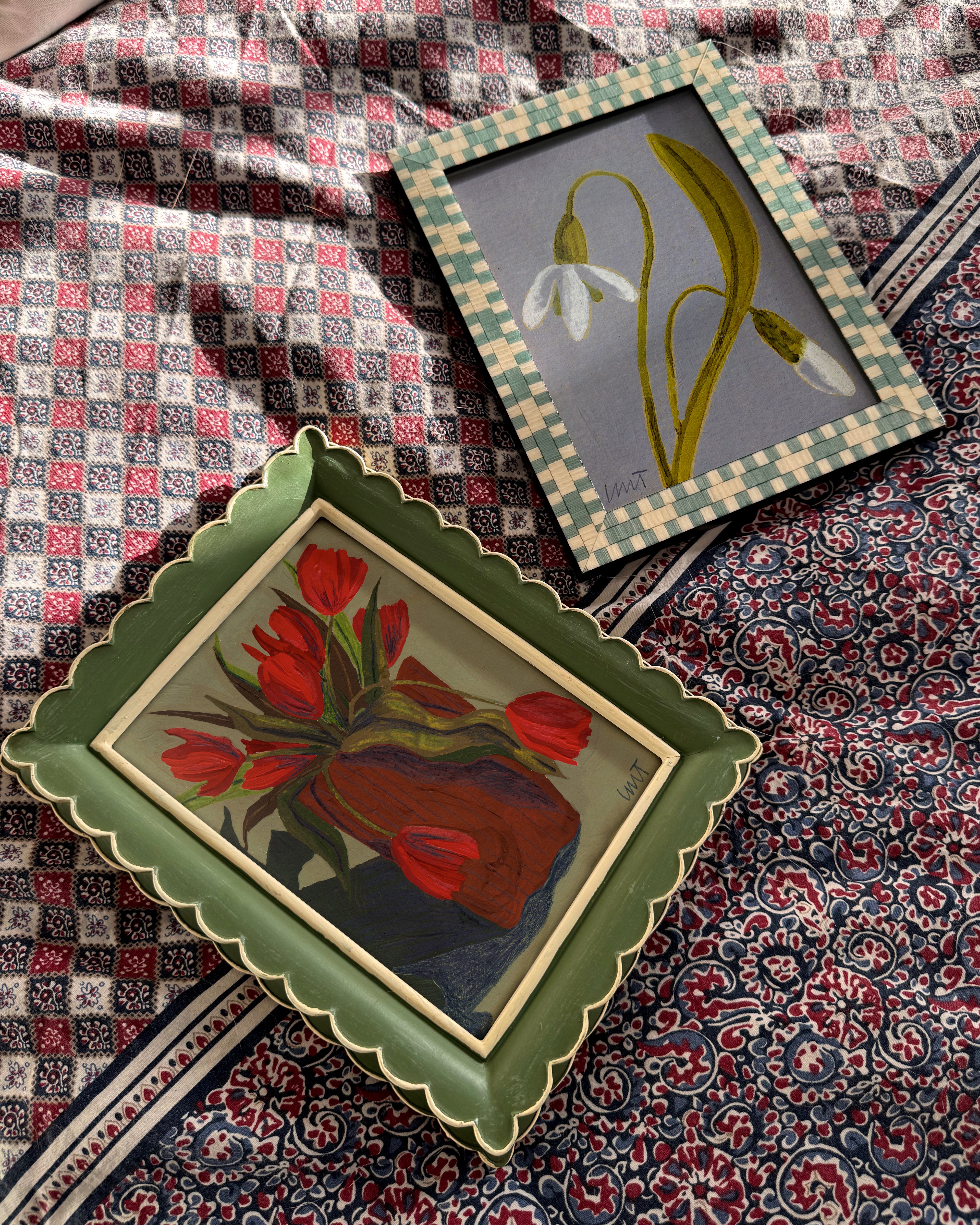 Two framed artworks on a patterned fabric background
